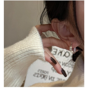 Gros plan de boucles d'oreilles créoles multicouches en argent portées à l'oreille