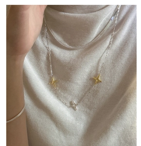Détail d'un collier multicouche en argent 925 avec pendentifs étoiles bicolores