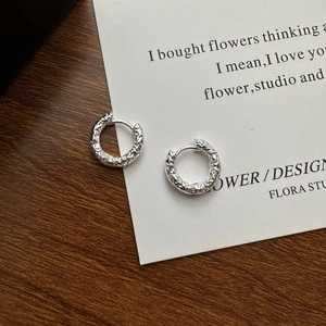 Minimalist S925 sterling silver hoop earrings with a textured hammered finish on a wooden table