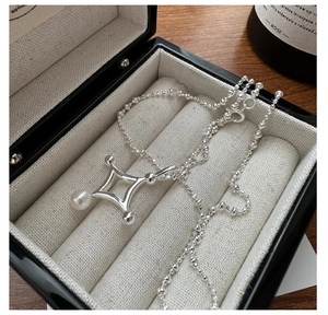 Détail d'un collier en argent S925 avec pendentif étoile et perle sur un coffret luxe