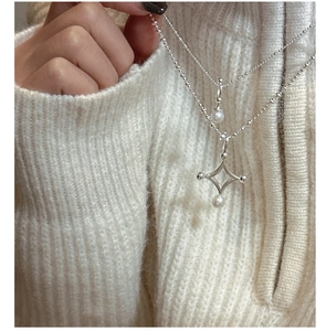 Détail d'un collier double rang en argent S925 avec perles et étoile sur pull beige