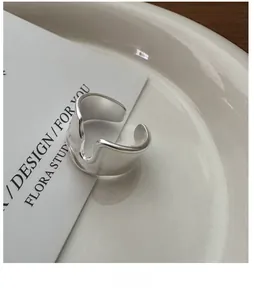 Detail view of minimalist silver U-shaped open ring with matte finish on white ceramic