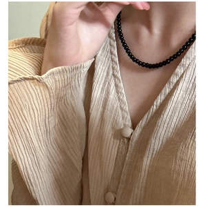 Detail shot of a beaded black onyx necklace on a model with minimalist styling