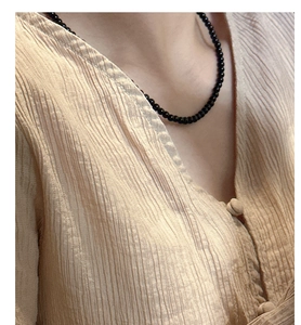 Close-up of S925 sterling silver black onyx beaded necklace on a model's neckline