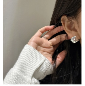 Close-up of minimalist S925 sterling silver square stud earrings and a thin ring on a model