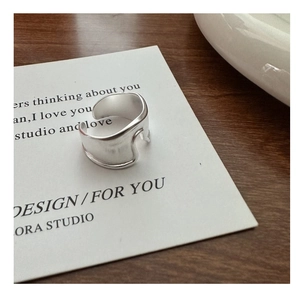 Detail of matte silver open ring with minimalist irregular wave design on wood surface