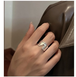 Close-up of liquid metal wave silver ring on finger with dark leather background