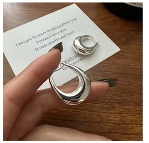 Detailed view of chunky S925 silver U-shape earrings with a polished mirror finish