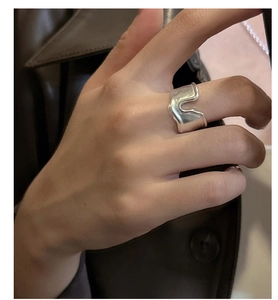 Close-up of S925 sterling silver wide band ring with irregular wave design worn on index finger