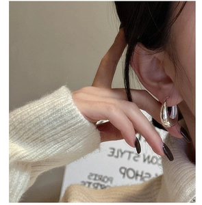 Detail of polished S925 sterling silver chunky U-shape hoop earring worn by a model