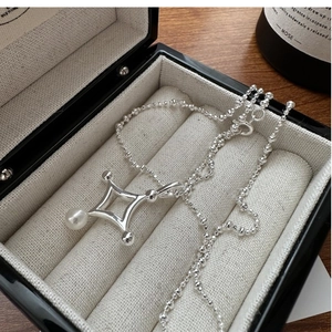 Détail du collier étoile en argent S925 avec perle blanche sur tissu de luxe