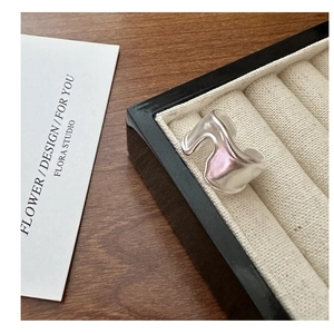 Macro shot of liquid metal style S925 sterling silver ring on a beige velvet jewelry box