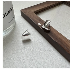 Detailed close-up of polished silver square hoop earrings on a textured surface