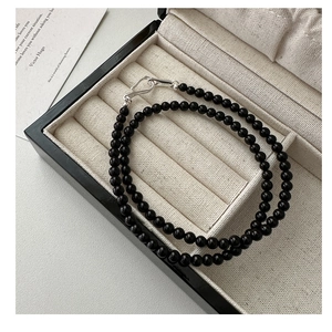 Close-up of black onyx beaded necklace with silver S-hook clasp in a premium jewelry box
