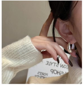 Close-up of polished S925 sterling silver U-shaped hoop earring on model in knit sweater