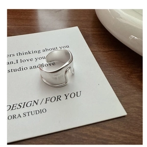 Detail of silver adjustable wide band ring with a brushed matte texture on wooden surface