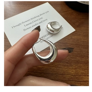 Macro shot of silver U-shaped chunky hoop earrings with high-polish mirror finish