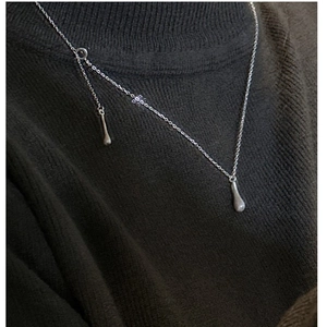 Détail macro du pendentif goutte en argent sterling S925 brossé sur un pull en tricot