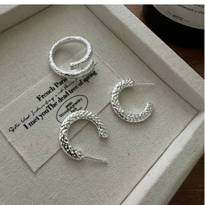 Detail of S925 sterling silver cross ring and C-shaped earrings with hammered texture