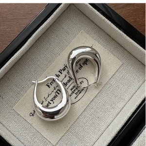 Detailed view of polished S925 sterling silver U-shaped earrings in a jewelry box