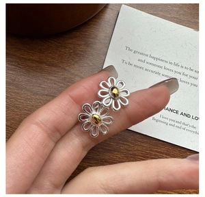 Detail of S925 sterling silver daisy stud earrings with silver petals and gold center