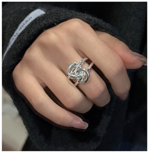 Detail of silver S925 knotted multi-layer ring on model's hand with textured cuff