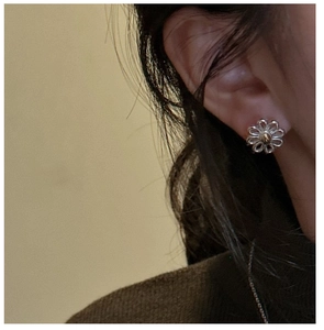 Close-up of S925 sterling silver daisy stud earrings worn on model for a trendy look