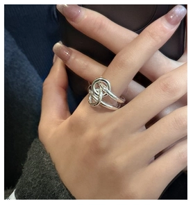 Close-up of S925 sterling silver knotted ring on finger showing polished metallic texture