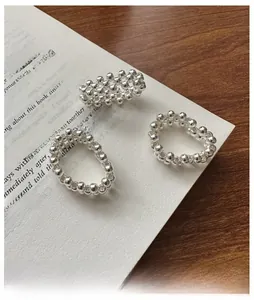 Detailed view of three handmade woven sterling silver rings on a rustic wooden table