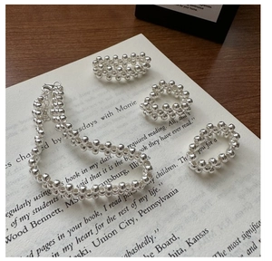 Detail of beaded sterling silver jewelry set featuring a necklace and rings on book pages