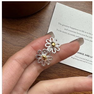 Close-up of S925 sterling silver daisy earrings with gold and silver contrast colors