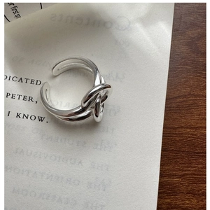 Detailed close-up of S925 sterling silver knotted ring on minimalist aesthetic background