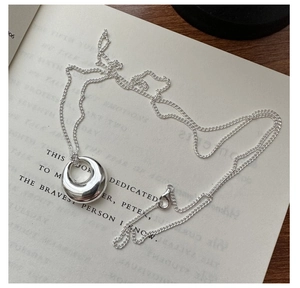 Detailed view of a silver 925 ping'an buckle pendant on a vintage book backdrop