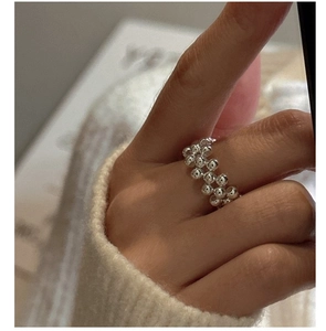 Detail view of a multi-row silver beaded ring styled with a white knitted sweater