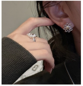 Detail of silver daisy flower ring and matching stud earrings on female model