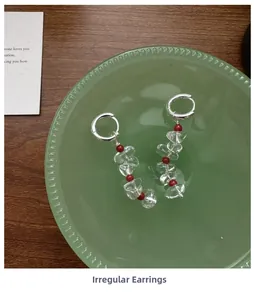 Close-up of S925 silver irregular hoop earrings with white crystal beads in a green tray