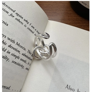 Detailed view of an S925 sterling silver knotted ring on a minimalist book page