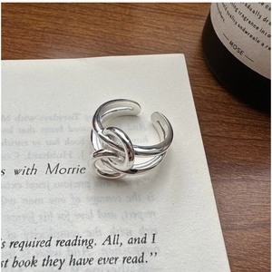 Macro shot of S925 sterling silver knotted ring on a book page with natural lighting
