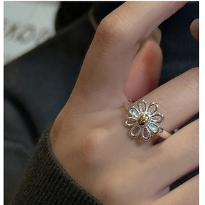 Close-up of S925 sterling silver daisy ring with gold center on a model's finger