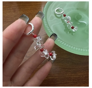 Macro shot of silver drop earrings with transparent quartz and vibrant red beads