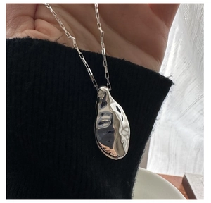 Macro shot of liquid texture silver pendant with textured surface and rectangle link chain