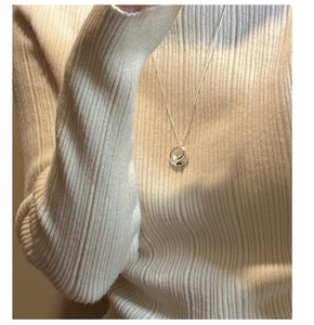 Detail of 925 silver double ring pendant necklace worn on a beige knit sweater