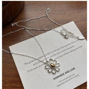 Close-up of S925 sterling silver daisy necklace with golden center on wood background