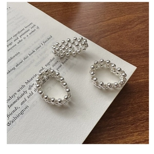Detailed view of 925 silver beaded rings and woven mesh band on a vintage book