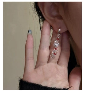 Detail of silver drop earring with red beads and clear crystals shown on a model