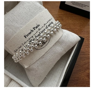 Macro detail of S925 sterling silver triple-layer beaded bracelet on a display cushion