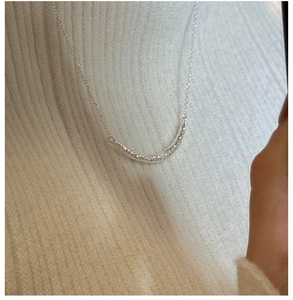 Gros plan d'un collier sourire en argent avec texture martelée sur fond tricoté