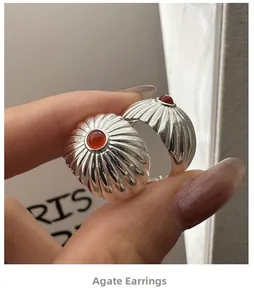 Close-up of S925 silver earrings with red agate stone and radial texture patterns