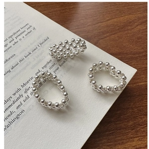 Macro detail of three-piece silver beaded rings showing woven metal texture and luster