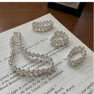 Detailed view of 925 sterling silver woven ball rings and necklace on vintage book pages